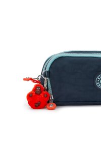 Borsa blu navy con cerniera turchese, caratterizzata da un portachiavi a forma di gorilla peloso rosso e un ciondolo circolare, realizzata in tessuto resistente.