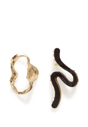 Deux barrettes décoratives, une dorée avec un contour ondulé et une autre en émail noir avec une forme courbée et abstraite.