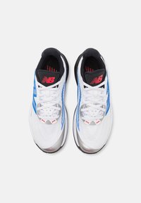 White athletic shoes with blue accents, silver midsole, black collar, and red branding. Features textured upper and flat laces.