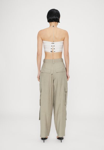 Top bianco accorciato con dettagli in bottone sulla schiena, abbinato a pantaloni cargo beige con tasche laterali e un fit morbido.