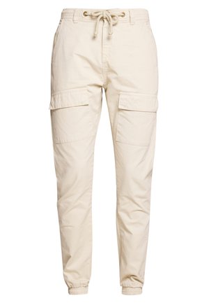Pantaloni cargo beige in tessuto leggero con vita elasticizzata e coulisse, due grandi tasche laterali e polsini aderenti alle caviglie.