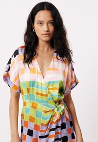 Kleurvolle wikkeljurk met een ruitpatroon in tinten van roze, groen, oranje en blauw, met korte mouwen en een strikdetail in de taille.