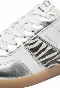 Sneaker bianca con punta e dettagli in argento metallico, pannello laterale a righe zebrate e design classico con lacci. Suola in gomma.