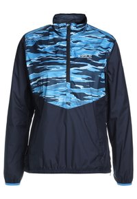 Halvdraget jacka med blå och svart abstrakt kamouflage mönster på bröstet, enfärgade mörka ärmar och torso, elastiska ärmmuddar, och "Jack Wolfskin"-logotyp på bröstet.