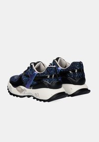 Zapatillas negras y moradas con detalles iridiscentes y brillantes, suelas gruesas blancas y suelas texturizadas negras, mostradas desde la parte trasera y lateral.