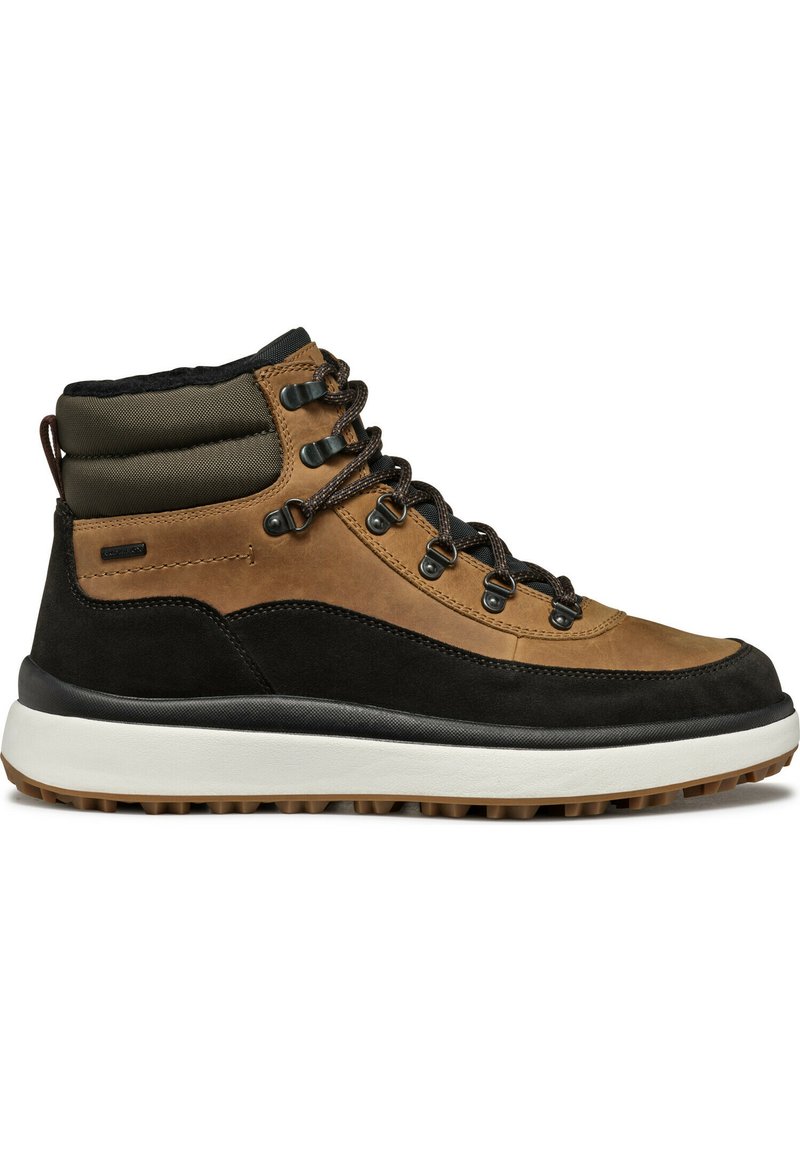 Bottines de randonnée imperméables marron avec une base en suède noir, un col rembourré vert et des œillets en métal. Elles présentent une semelle en caoutchouc texturée.
