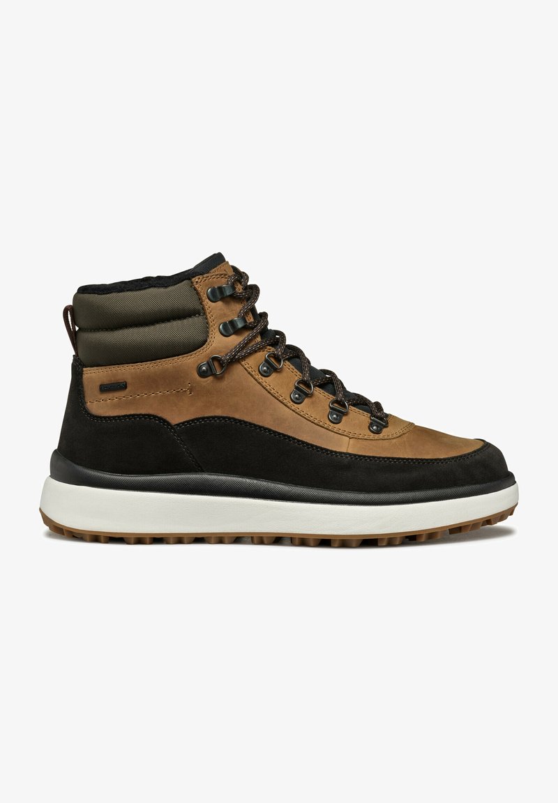Braune wasserdichte Wanderschuhe mit einem schwarzen Wildleder-Basis, gepolstertem grünen Kragen und Metallösen. Sie verfügen über eine strukturierten Gummisohle.