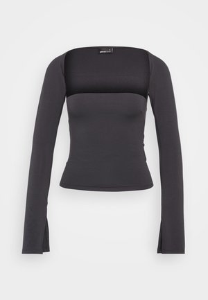 Juodas ilgomis rankovėmis viršus su kvadratiniu iškirpimu, prigludusia siluetu ir šoninėmis išpjovomis apačioje. Pagamintas iš glotnaus, elastingo audinio.