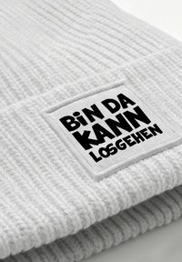 Gray knitted beanie with a ribbed texture and a white patch displaying the phrase "Bin Da Kann Losgehen" in bold black letters.