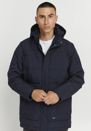 Navy puffer jacket with a hood, featuring a front zip and snap button closure, side pockets, and a quilted texture.