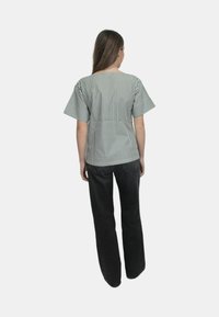 Top a righe, a maniche corte e dal fitting morbido, con linee verticali verdi e bianche, abbinato a jeans larghi scuri.