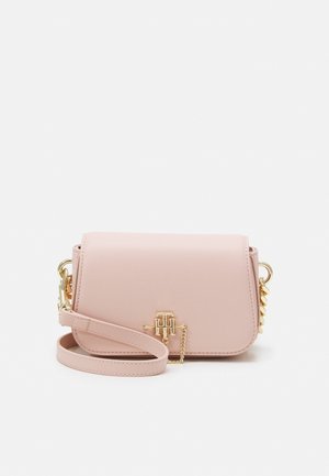 Jasnoróżowa skórzana torebka na ramię z akcentami w postaci złotego łańcuszka oraz złotym logo „TH” na przedniej klapce zamykającej.