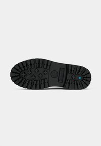 Soletta in gomma nera con scanalature profonde, dotata di un logo centrale e un accento blu vicino all'alluce. Design resistente e testurizzato per una maggiore aderenza.