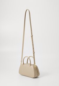 Borsa a mano in pelle beige con una forma strutturata e arrotondata, due manici superiori e una tracolla lunga removibile. Presenta una zip e accessori in oro.