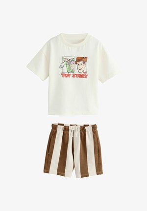 Ținută pentru copii cu tricou alb Toy Story, având imagini cu Buzz Lightyear și Woody, asortată cu pantaloni scurți în dungi verticale maro și albe.