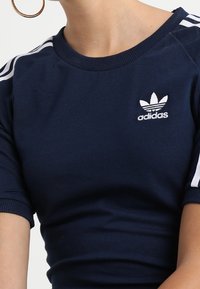 Navy blue cotton t-shirt with white three-stripe design on sleeves and an embroidered Adidas logo on the chest. Fitted design.