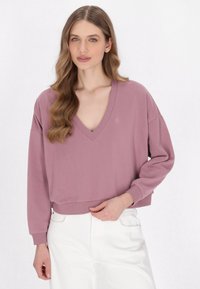 Felpa corta a maniche lunghe con scollo a V di un tenue color malva, realizzata in tessuto morbido con polsini e orlo a coste. Dettaglio del logo discreto sul petto.
