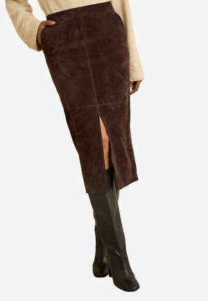 Brauner Wildleder-Bleistiftrock mit einem hohen Schlitz. Glatte Textur, figurbetonte Silhouette und mittellanges Design. Tragen mit schwarzen kniehohen Stiefeln.