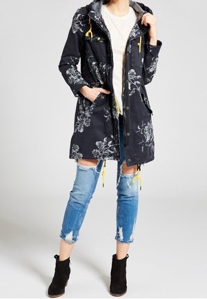 Wodoodporna parka w granatowy kwiatowy wzór, z zamkiem z przodu, sznurkiem w talii i żółtymi akcentami. Noszona na lekką bluzkę i zniszczone dżinsy.