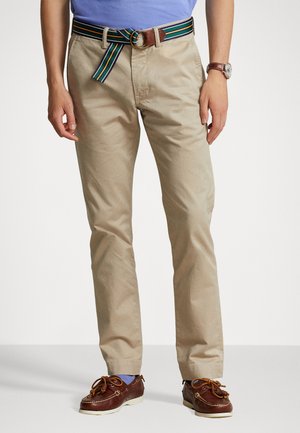 Beige chino's met een rechte snit, gecombineerd met een meerkleurige gestreepte riem en bruine leren schoenen met veters.