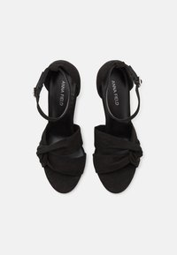 Svarta mocka högklackade sandaler med en knuten design fram, vristrem med spänne och slät innersula.
