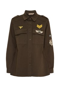 Brun skjorta med långa ärmar, knäppning framtill, två bröstfickor och militärstilspatchar inklusive bin och vingar.