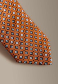 Narancssárga selyem nyakkendő, amelyen geometriai mintázat található apró kék és fehér négyzetekből, virágos motívumokkal kiegészítve. Sima textúrájú, szabványos nyakkendőforma.