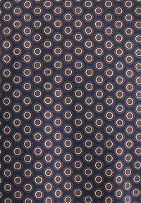 Tessuto navale con una stampa di cerchi uniformemente distribuiti; i cerchi interni sono marroni con contorni bianchi. Il materiale appare liscio e simile a un tessuto.