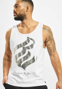 Tricou fără mâneci alb, cu un design grafic argintiu proeminent și textul "Established New York 2000" în partea de jos. Material din bumbac neted.