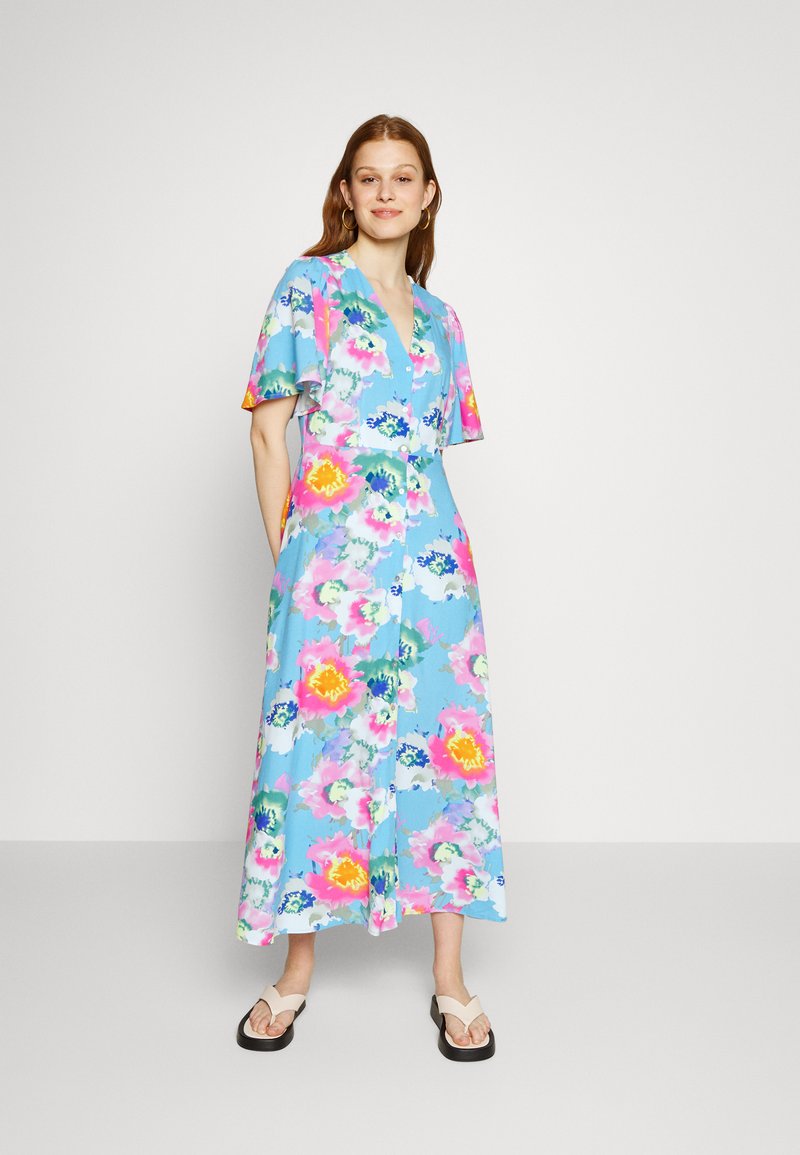 Vestido maxi floral com um fundo azul claro, adornado por flores vibrantes em rosa e amarelo, mangas curtas e um fecho frontal com botões.