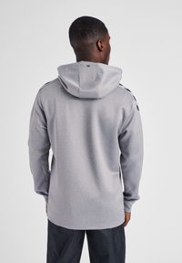 Grijze hoodie met een gestructureerde afwerking, voorzien van lange mouwen, een trekkoordcapuchon en contrasterende strepen op de schouders. Eenvoudig ontwerp aan de achterkant.