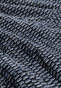 Tissu bleu marine avec un motif répétitif de fines rayures blanches et bleu clair, présentant une apparence texturée et froissée.