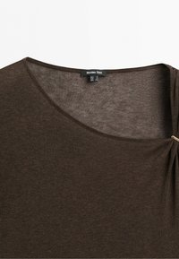 Tmavě hnědý pletený top s kulatým výstřihem a malým záhybem na jedné straně zajištěným kovovou sponou, štítek ukazuje Massimo Dutti.