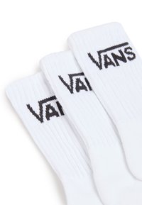 Vita bomull crew strumpor med ribbat mönster, med en framträdande svart "VANS"-logotyp på midjan. Tre par staplade tillsammans.