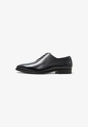 Black leather dress shoe with a sleek, rounded toe and a low heel. Features lace-up closure and a shiny finish. Smooth texture throughout.