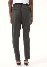 Pantaloni slim-fit di colore verde oliva realizzati in tessuto morbido, con vita media, due tasche posteriori e caviglie affusolate.