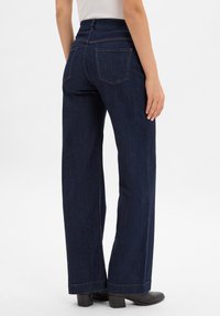 Spodnie dżinsowe w ciemnym kolorze z szerokimi nogawkami, wysokim stanem, tylnymi kieszeniami oraz kontrastowymi szwami.