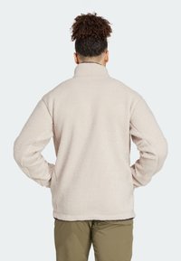 Giacca in pile color crema, soffice e voluminosa, con collo alto, maniche lunghe e vestibilità rilassata, caratterizzata da tessuto testurizzato e fodera interna liscia.