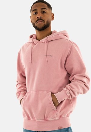 Sudadera rosa claro con capucha ajustable, bolsillo tipo canguro, puños acanalados y dobladillo. El tejido parece suave y ligeramente texturizado.