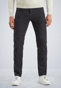 Šedé džíny vyrobené z denimu s texturovaným povrchem, s pěti kapsami a slim fit, v kombinaci s bílými teniskami pro kontrast.