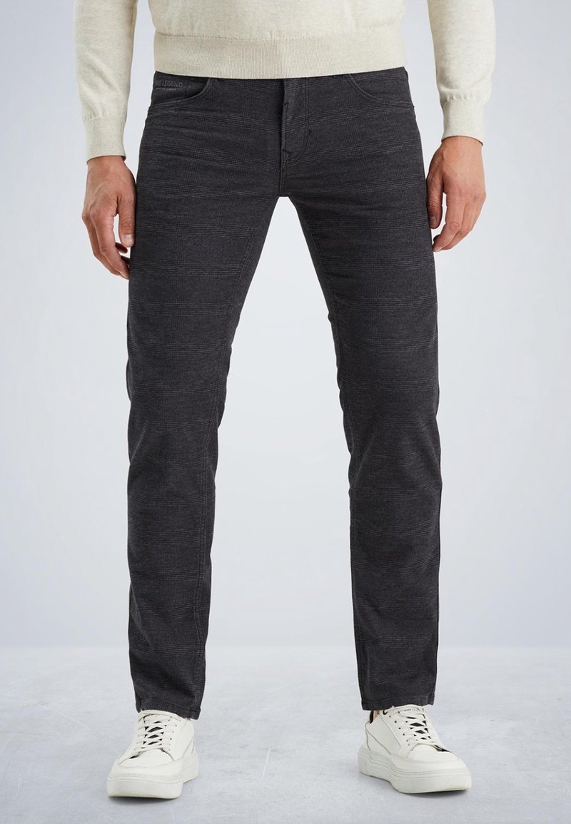 Šedé džíny vyrobené z denimu s texturovaným povrchem, s pěti kapsami a slim fit, v kombinaci s bílými teniskami pro kontrast.