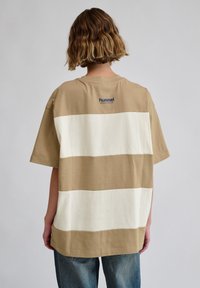 Beige og hvidstribet bomulds T-shirt med rund halsudskæring, korte ærmer og et logo på ryggen. Casual, afslappet pasform.