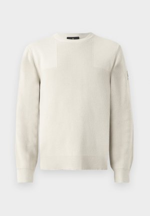 Cream-colored knit sweater with a crew neck, ribbed texture, and contrasting panel details on the chest and shoulders.