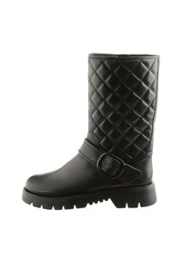 Black mid-calf boot with quilted upper, thick lug sole, rounded toe, and decorative strap with a large buckle on the side.