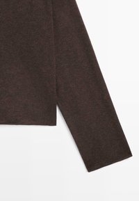 Top a maniche lunghe marrone scuro realizzato in morbido tessuto lavorato a maglia, caratterizzato da un orlo dritto e un taglio rilassato con dettagli di cuciture visibili.