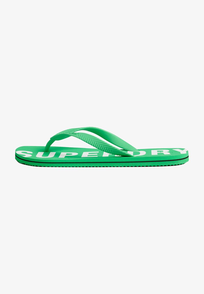 Groene rubberen slippers met textuur op de banden en een witte "SUPERDRY" logo op de zool, getoond vanuit een zijaanzicht.
