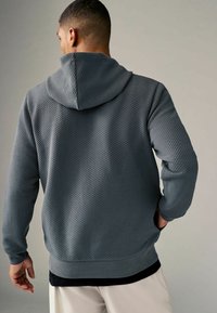 Grijze, gewatteerde hoodie met een ruitpatroon, geribbelde manchetten en zoom, met een losse pasvorm en een zachte, geweven stof.