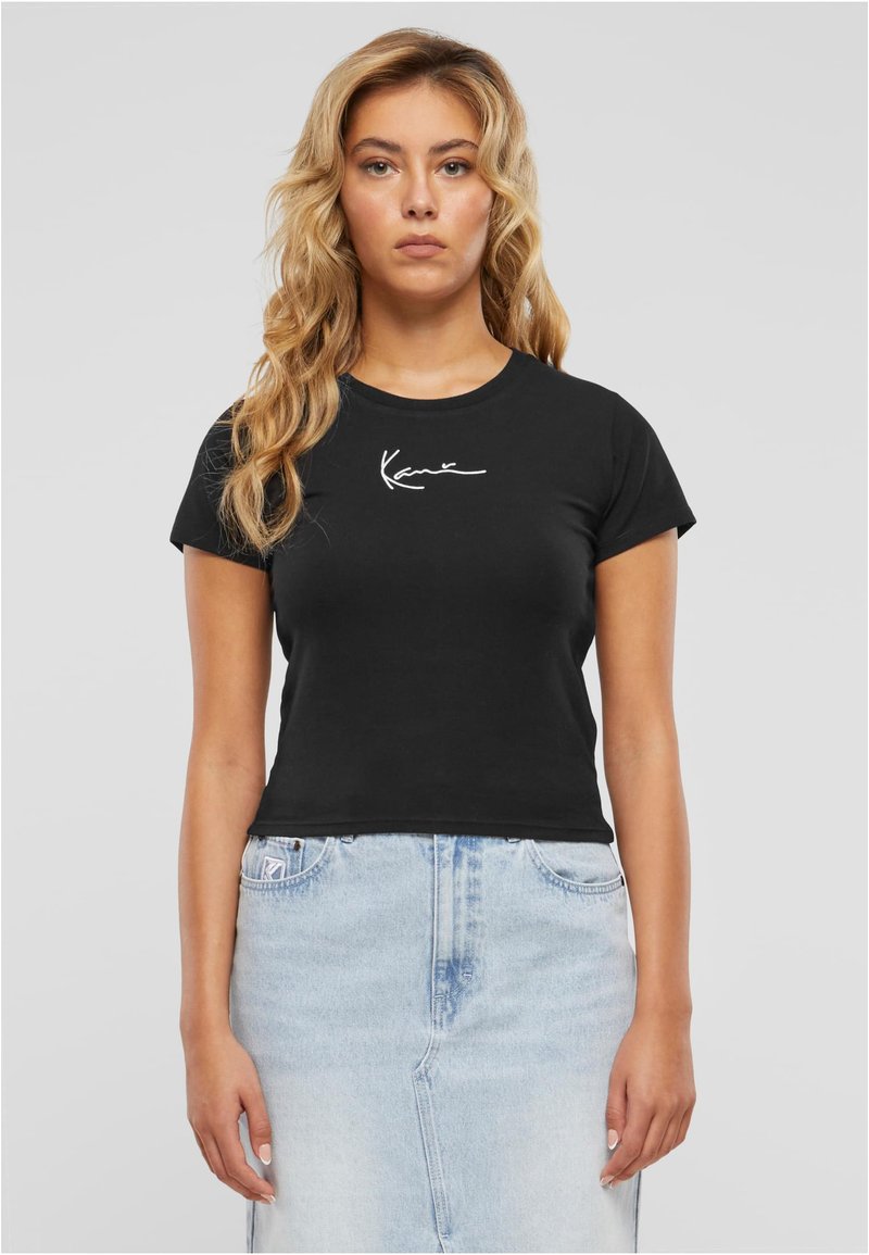 Must musta T-särk lühikeste varrukatega, liibuv disain ja valge allkirja print rinnal, koos helesinise teksaseelikuga.