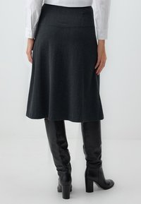 Donkergrijze flared rok van textiel, met een soepele tailleband. Gecombineerd met zwarte kniehoge laarzen. Eenvoudig en elegant ontwerp.