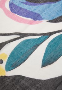 Tissu présentant des motifs floraux abstraits en rose, bleu et turquoise sur fond blanc, avec des contours noirs et une texture douce.